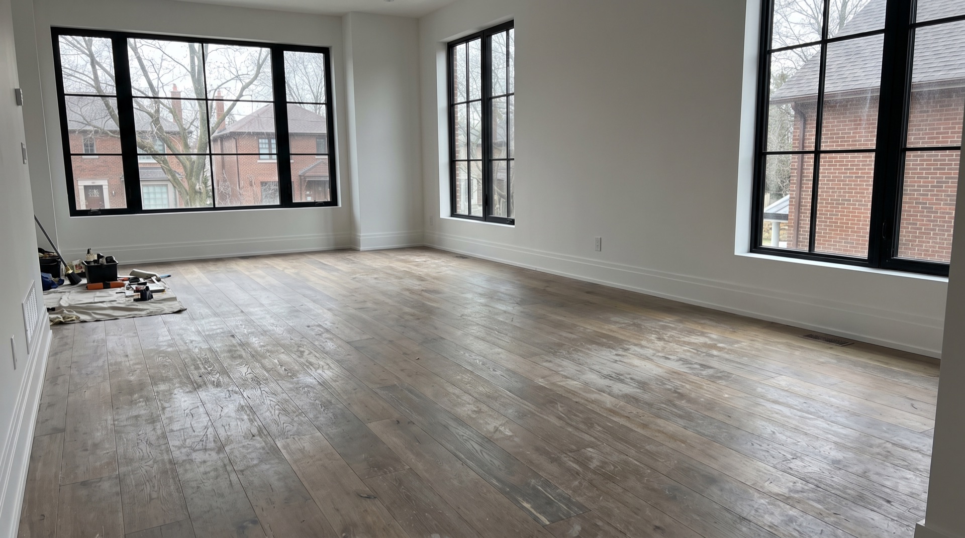 Modern living room with a worn hardwood floor before refinishing
